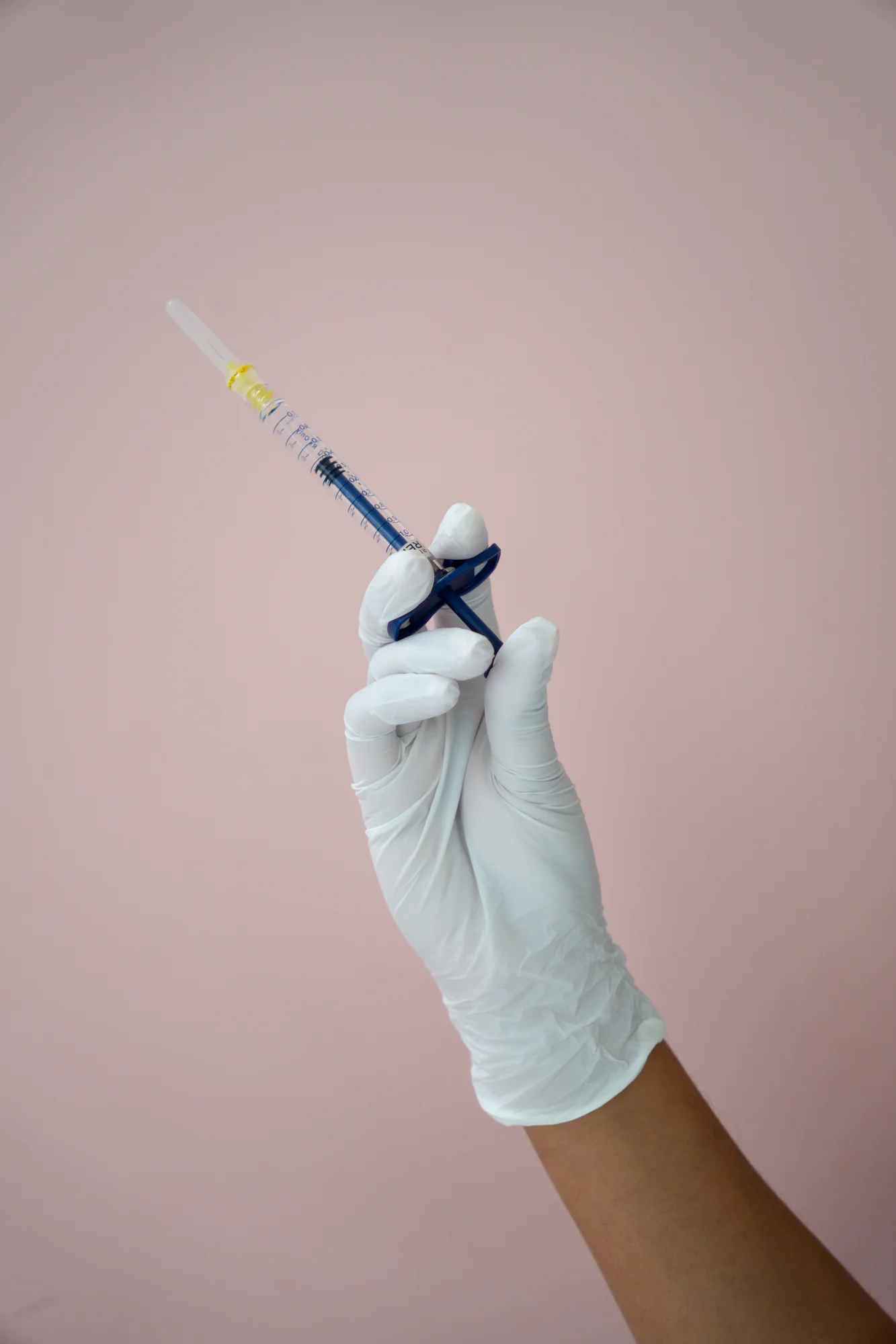 A drawn-up neuromodulator syringe in a gloved hand at Skin Talk